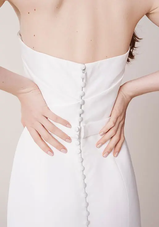 1627409711489-marne-back Marne, an ivory strapless fit-and-flare bridal gown in luxurious matte satin, featuring a flattering banded waist and a full line of delicate buttons cascading down the center back.