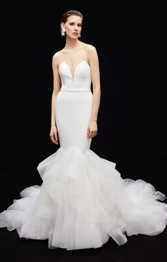 Kiera, an ivory strapless mermaid bridal gown by Alyne by Rita Vinieris. It features a crepe bodice with a modified sweetheart V-neck plunge, a fitted silhouette through the hips, and a voluminous tiered tulle ruffled skirt and train.