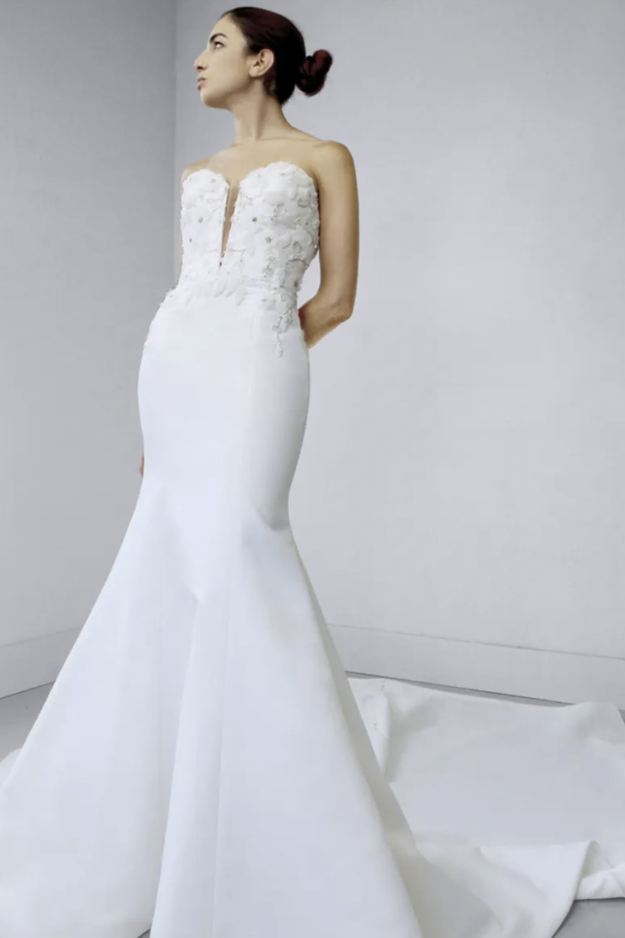 1659120300786-screen-shot-2022-07-29-at-2-44-14-pm Ady, an enchanting full-length ivory matte satin fit-and-flare wedding gown, features a strapless sweetheart plunge bodice intricately adorned with hand-appliquéd beaded lace.