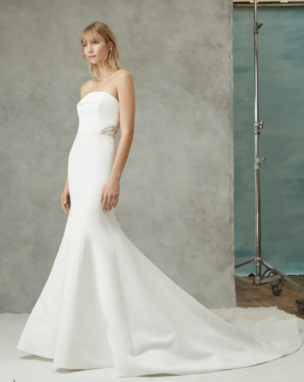 Arya, an ivory strapless satin mermaid wedding gown with a fit-and-flare silhouette, delicate applique and lace detailing at the waist, and a chapel train.
