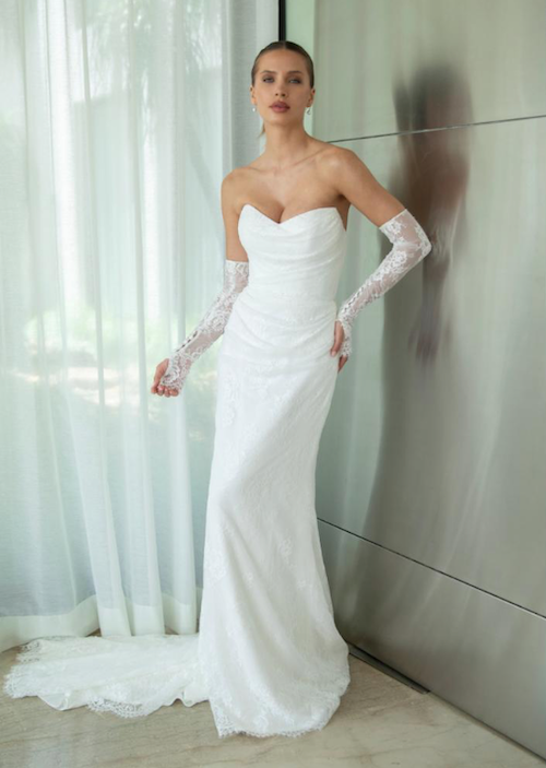 Madison, an ivory Mariana Hardwick bridal gown, size 14AU, featuring a strapless modified sweetheart neckline, a draped and pleated bodice, and a natural waist. The lace gown has a fit-n-flare sheath silhouette with a subtly draped skirt and a chapel-length train.
