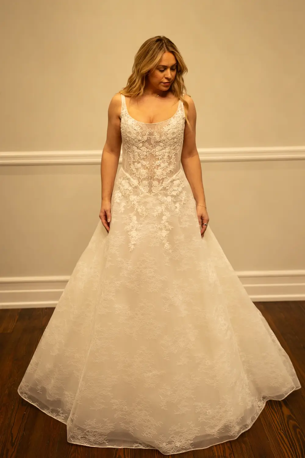 Savanna, an ivory A-line bridal gown by Sincerely Adorn with a demi-sheer basque bodice, scoop neckline, and spaghetti straps, adorned with delicate lace appliqué and beading, and a chapel train.