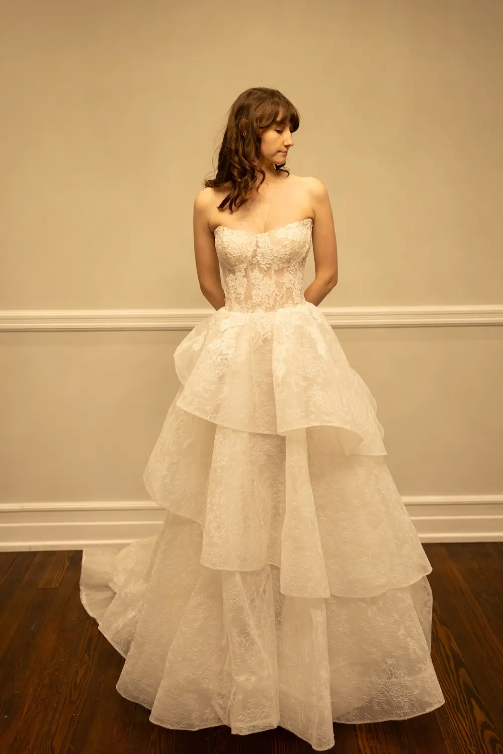 Florence, an ivory bridal gown with a demi sheer strapless lace bodice and a dramatic A-line skirt featuring asymmetric ruffles and a floor-length hem.