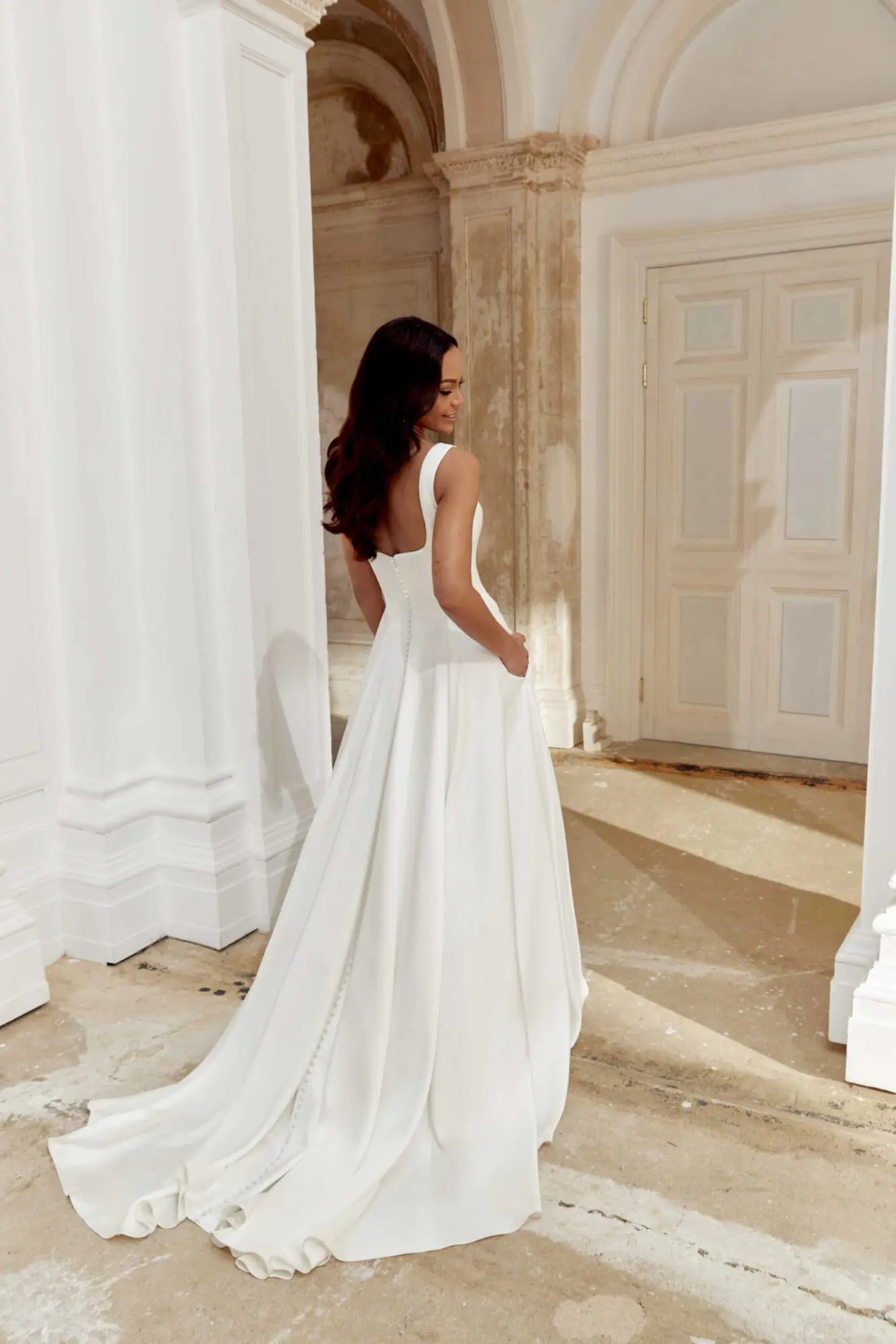 uploads-1746476614548_img_44548_fb_sincerity-bridal_36 Charmeuse-covered buttons trail down the back, extending to the puddle-length train, and hidden pockets complete this effortlessly sophisticated design.