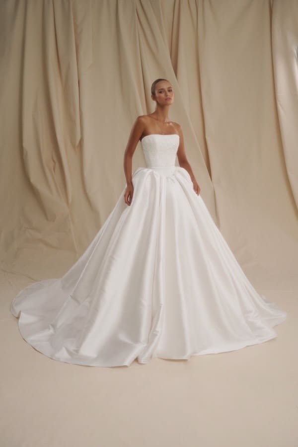 1720731492316-image-8-2 SE001, a Diamond White strapless ball gown by Senstudio, featuring a delicate lace bodice with clear sequins over a Basque waistline, and a lustrous mikado skirt with a cathedral train.