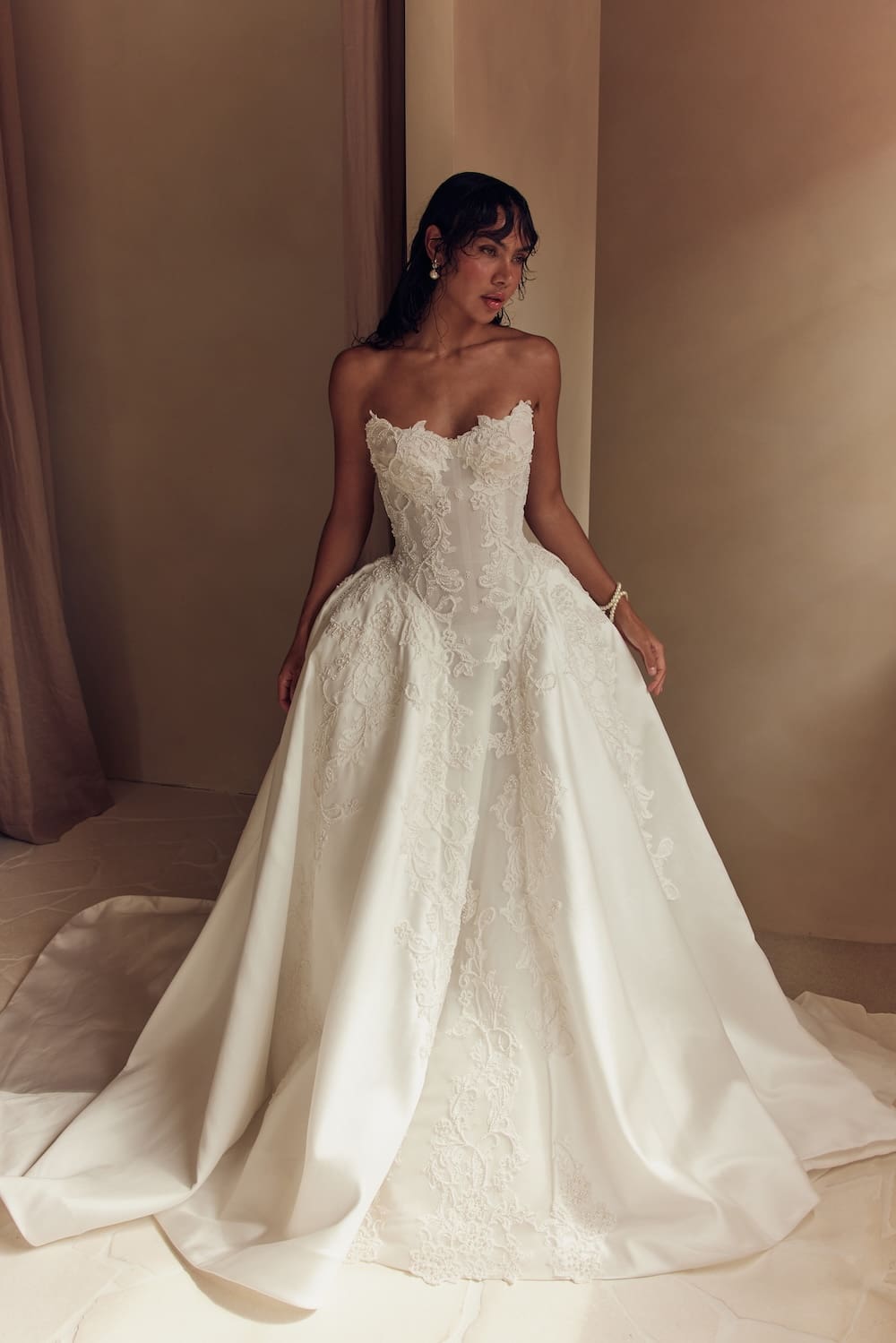 1747162918880-Leah-Da-Gloria_09_016 Alexandra, an ivory strapless sweetheart ball gown wedding dress with a Basque waist, featuring intricate lace and shimmering beaded embroidery on a dramatic mikado skirt with a cathedral train.