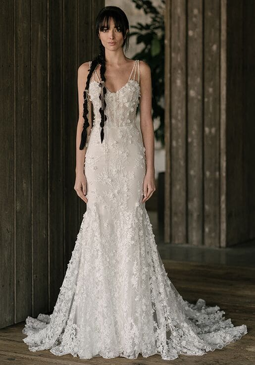 1616279565293-3fef0976-fee7-48aa-b078-8ad21c027be7 Hayward, an ivory fit-and-flare bridal gown by Rivini, featuring a sweetheart neckline and delicate spaghetti straps. The dress is intricately embellished with lace appliques and beading throughout, extending into a sweep train.