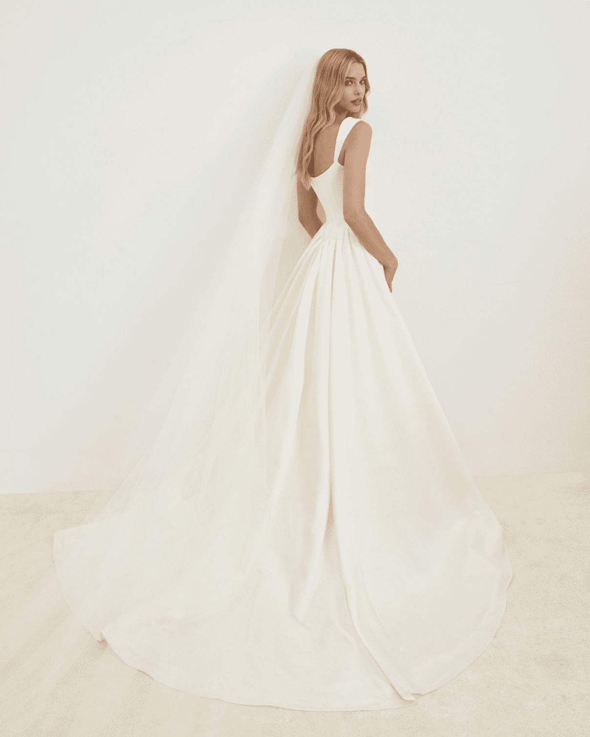 1737837880041-screen-shot-2025-01-25-at-3-44-14-pm SE042, a cream bridal gown with a modified square neckline, features an exaggerated panel train, creating a dramatic and striking silhouette.