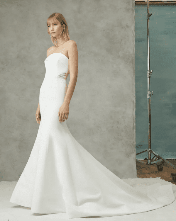 Arya, an ivory strapless satin mermaid wedding gown with a fit-and-flare silhouette, delicate applique and lace detailing at the waist, and a chapel train.