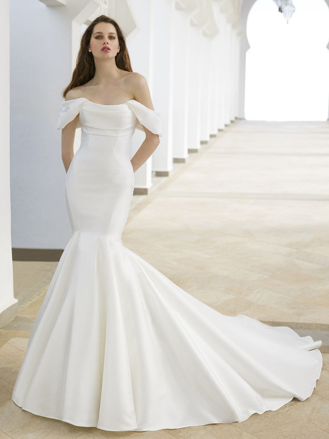 1759258741764-24_Blue_PRO__RORY_Fro_Web_1064_1418_80_s_c1 Rory, an ivory Mikado bridal gown by Blue by Enzoani, showcasing an off-the-shoulder draped bodice with a scoop neckline, a flattering fit-and-flare silhouette, a dramatic cathedral train, and button detailing.